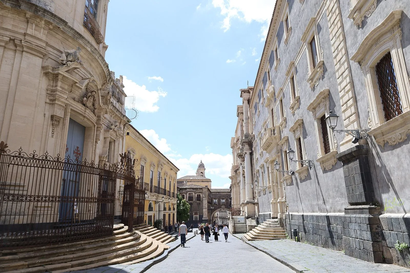 Via dei Crociferi a Catania con la facciata curva della chiesa di San Giuliano a sinistra, palazzi barocchi e l'Arco di San Benedetto sullo sfondo