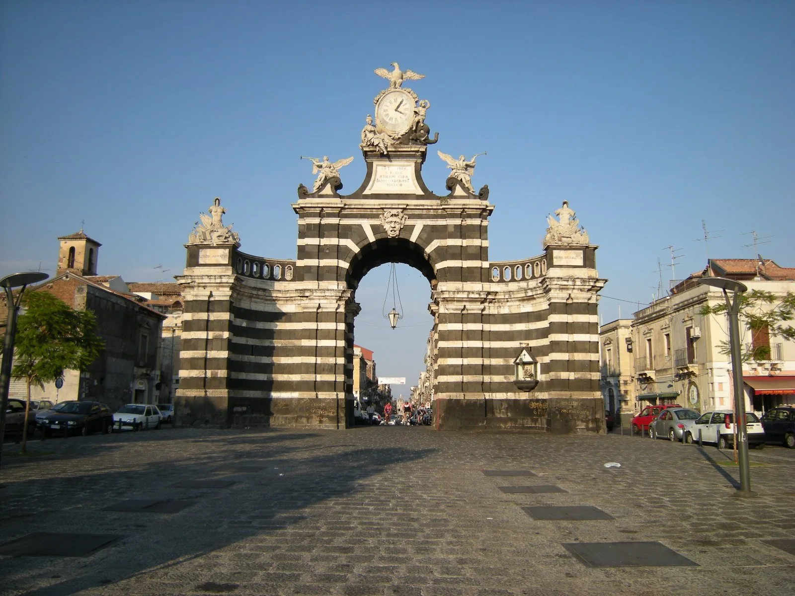 Porta Garibaldi a Catania, arco monumentale a fasce alternate di pietra lavica nera e pietra bianca, con la piazza in basolato