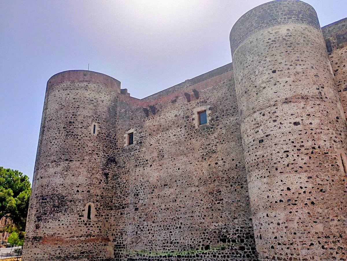 Castello medievale in pietra con torri angolari affacciato su piazza